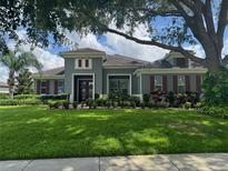 Well-manicured front yard and mature trees adorn this lovely single-Gathering home with red shutters at 25863 Crossings Bluff Ln, Sorrento, FL 32776