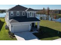 Charming two-story home featuring a two-car garage and beautiful landscaping backing onto a serene lake view at 2609 Village Lakes Blvd, Lakeland, FL 33805