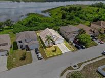 An aerial view of a single-Gathering home near a lake with a well-manicured lawn and mature landscaping at 2740 Rochelle Dr, Winter Haven, FL 33881