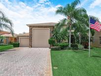 Charming two-story home features a stone facade, well-manicured lawn, and palm trees at 4105 Limerick Dr, Lake Wales, FL 33859