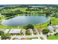 An aerial view shows the house with lake access, a nearby pool, and mature landscaping at 464 Lake Suzanne Dr, Lake Wales, FL 33859
