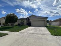 Charming single-story home featuring a spacious front yard, driveway, and attached two-car garage at 4747 Mandolin Loop, Winter Haven, FL 33884