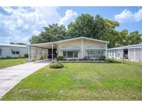 Inviting single-story home featuring a well-maintained lawn, covered carport and manicured landscaping at 6027 Grand Oaks Se Dr, Winter Haven, FL 33884