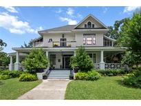 Beautiful two-story home with a charming front porch, manicured lawn, and mature trees at 103 Se Tuscawilla Ave, Ocala, FL 34471