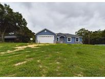 Charming one-story blue home with a two-car garage and stone accents at 1264 Buckeye Ne Rd, Winter Haven, FL 33881