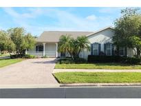 Charming home featuring a welcoming front porch, brick driveway, and lush landscaping at 130 Prima Dr, Kissimmee, FL 34759