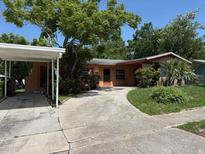 Charming single-story home featuring a covered carport, mature trees, and a concrete driveway at 1506 Fairbanks St, Lakeland, FL 33805