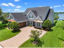 Stunning lakefront home features a manicured lawn, brick driveway and a three car garage at 1836 Woodpointe Dr, Winter Haven, FL 33884