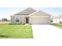 Tan house with a two-car garage and a well-manicured lawn at 322 Brennan Ave, Frostproof, FL 33843