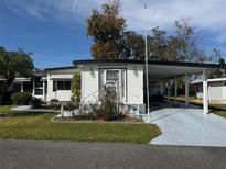 Single-wide manufactured home with carport and mature landscaping at 102 Willow Ln, Leesburg, FL 34748