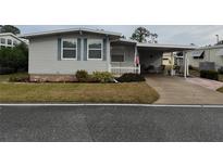 Single-wide manufactured home with covered carport and small front yard at 110 Dogwood Trl, Leesburg, FL 34748