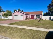 Pink house with a white garage door and nicely landscaped lawn at 1273 Tyler Lake Cir, Orlando, FL 32839