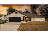 One-story home with a black garage door and landscaped yard at 16546 7Th St, Montverde, FL 34756