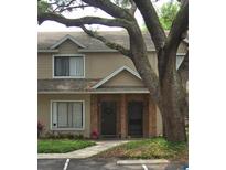 Two-story tan townhouse with a brick facade and a mature tree in the front yard, offering curb appeal at 255 Sandlewood Trl # 4, Winter Park, FL 32789