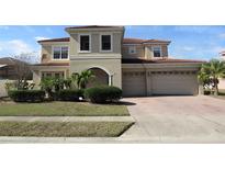 Charming two-story home featuring a tile roof, arched entryway, three-car garage and landscaped yard at 2802 Quiet Water Trl, Kissimmee, FL 34744