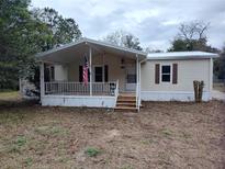 Tan single-wide manufactured home with covered porch and American flag at 3376 Se 94Th St, Ocala, FL 34480