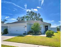 White house with a two-car garage and landscaped lawn at 4481 Reding Way, Lakeland, FL 33813