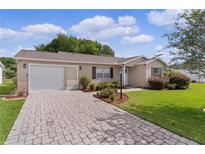 Charming home featuring a brick driveway, attached garage, and well-maintained landscaping at 1411 Juarez Pl, The Villages, FL 32159