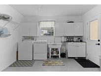 Bright laundry room features modern washer and dryer, ample cabinet storage, and convenient utility sink at 1411 Juarez Pl, The Villages, FL 32159