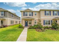 Tan two-story townhome with blue shutters and a grassy lawn at 1567 Candlefire Row, Kissimmee, FL 34744