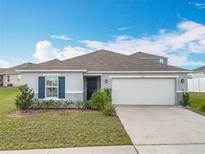 Charming single-story home with a two car garage, landscaped front yard, and a well-maintained lawn at 2369 Crossandra St, Mascotte, FL 34753