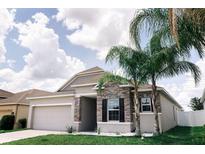 Charming single-story home with stone accents, lush lawn, and beautiful palm trees at 414 Taft Dr, Davenport, FL 33837