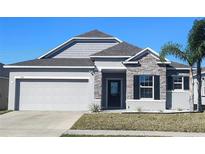 Charming single-Gathering home with a grey exterior, stone accents, and a two-car garage at 414 Taft Dr, Davenport, FL 33837