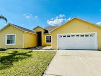 Charming yellow single-story home with an attached two-car garage and well-maintained lawn at 434 Acacia Tree Way, Kissimmee, FL 34758