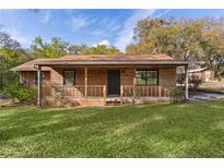 Charming single-story home featuring a cozy front porch, wood siding, and a well-manicured lawn at 1107 Linmar Ave, Fruitland Park, FL 34731