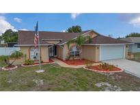 Charming single-story home featuring a well-manicured lawn, American flag, and attached two-car garage at 1134 Norwood Dr, Deltona, FL 32725