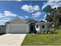 Charming single-Gathering home featuring a well-maintained lawn, attached garage, and neutral color palette at 141 W 6Th St, Frostproof, FL 33843