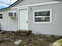The home's exterior features a window, air conditioner, and a white front door with steps at 309 Old Mission Rd, New Smyrna Beach, FL 32168