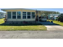 Charming mobile home with large windows and attached carport in a well-maintained community at 114 Caladium St, Leesburg, FL 34748