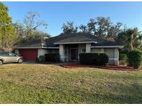 Charming single-story home with a red garage door, well-kept landscaping, and inviting curb appeal at 7741 Merrily Way, Lakeland, FL 33809