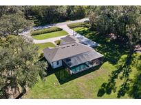 Aerial view of beautiful home with screened pool, lush green lawn, and mature trees at 15373 Evans Ranch Rd, Lakeland, FL 33809