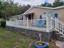 Inviting home exterior showcasing a white deck with white railings, blue shutters, and decorative yard features at 4814 Myrtle View N Dr, Mulberry, FL 33860