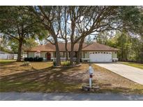 Charming one-story home with mature trees, a well-manicured lawn, and a two-car garage at 10441 Sw 54Th Ct, Ocala, FL 34476