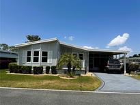 Charming single-story home with a carport, manicured lawn, and mature landscaping under a sunny sky at 106 Pyracantha Ln, Leesburg, FL 34748