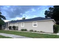Beautiful exterior showcasing well-maintained landscaping, gray stucco, and a dark shingle roof at 1833 Courtland St, Orlando, FL 32804