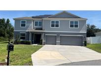 Beautiful two-story home featuring a two-car garage, grey siding, and solar panels on the roof at 1940 Bell Creek Loop, Fruitland Park, FL 34731