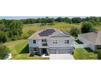 Two-story home with a three-car garage, manicured lawn, and solar panels at 1940 Bell Creek Loop, Fruitland Park, FL 34731