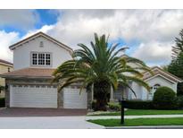 Charming two-story home featuring a three car garage, tile roof, and a tropical palm tree in the front yard at 2408 Dahlgren Way, Winter Garden, FL 34787