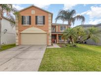 Charming two-story home featuring a large garage and well-maintained lawn with decorative palm trees at 709 Crystal Bay Ln, Orlando, FL 32828