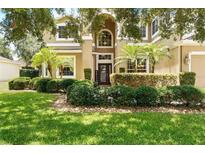 Charming two-story home featuring a manicured lawn, lush landscaping, and an inviting entrance at 1085 Harmony Ln, Clermont, FL 34711