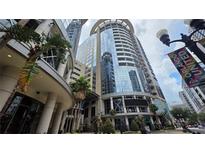 Contemporary building featuring expansive glass windows, street level statues, and lush palm trees at 155 S Court Ave # 1801, Orlando, FL 32801