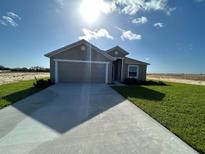 New construction home with a large driveway and attached two car garage and light landscaping at 2117 Emma Ln, Lake Wales, FL 33898