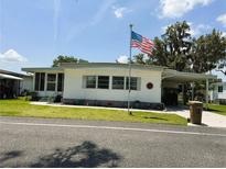 Charming single-story home featuring a covered carport, well-maintained lawn and an American flag at 313 Palo Verde Dr, Leesburg, FL 34748