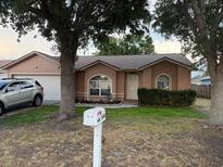 Charming single-story home featuring a well-manicured lawn, attached garage, and mature trees shading the front at 6616 Shepherd Oaks St, Lakeland, FL 33811
