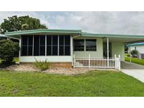 Charming light green home with screened porch and adjacent carport at 106 Azalea Trl, Leesburg, FL 34748