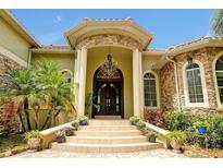 Stately home entrance with stone accents, double doors, chandelier, and manicured landscaping at 1502 Hempel Ave, Windermere, FL 34786
